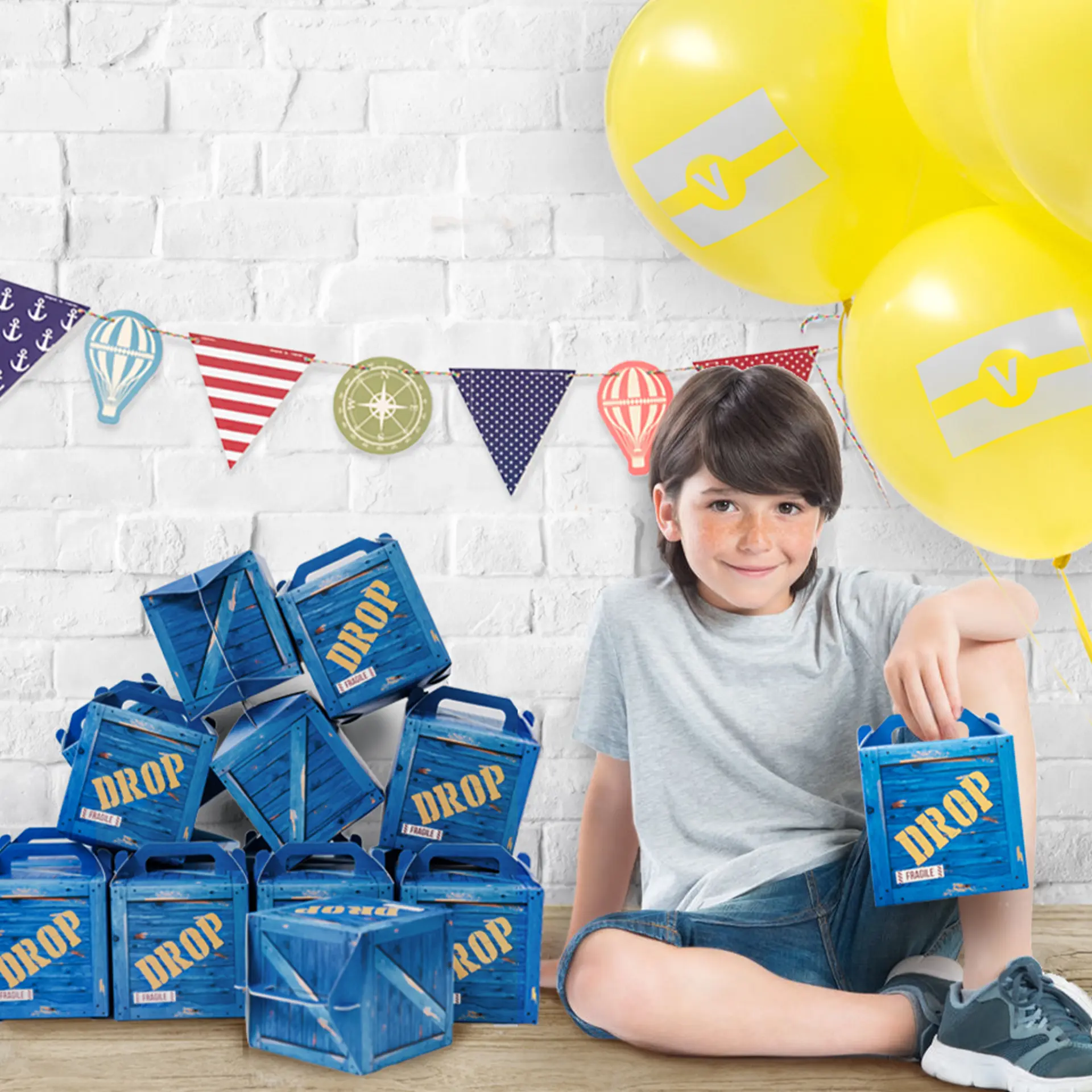 Boy with a stack of blue Drop crate party favor boxes and balloons